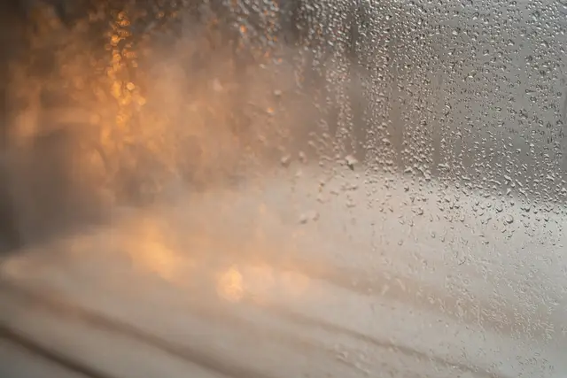Water droplets on glass with warm light blurred behind
