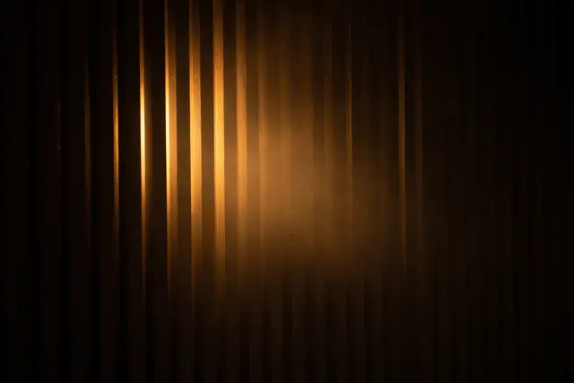 Warm amber light glowing through narrow vertical wood slats