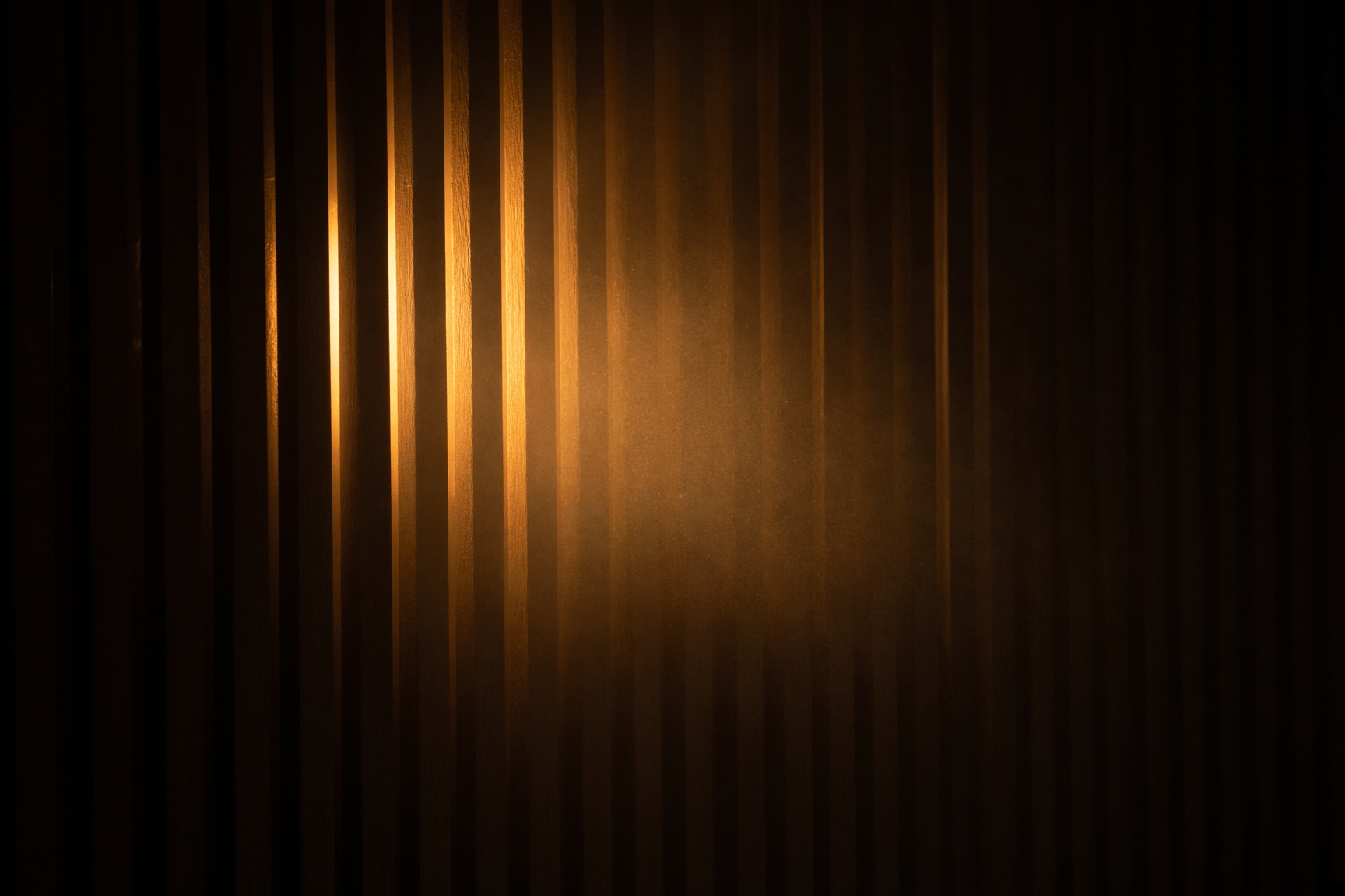 Amber light leaking through narrow vertical wood slats