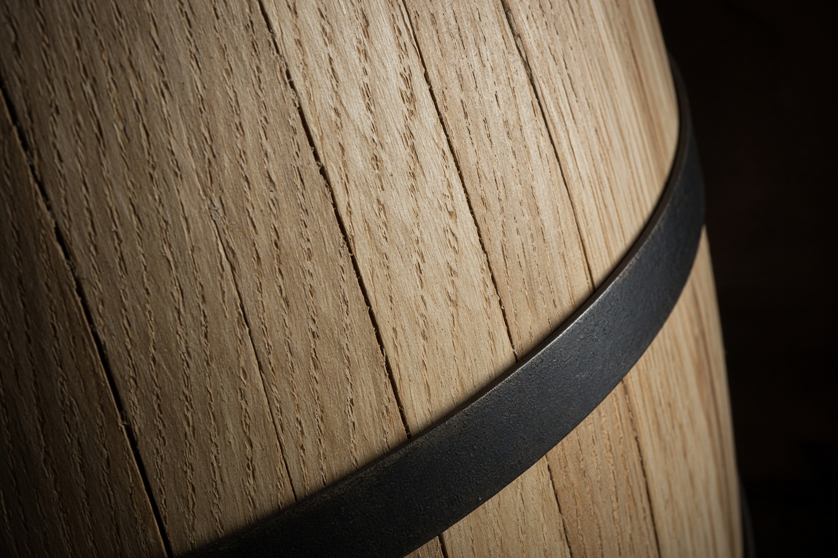 Close view of curved wood staves held by a dark metal band